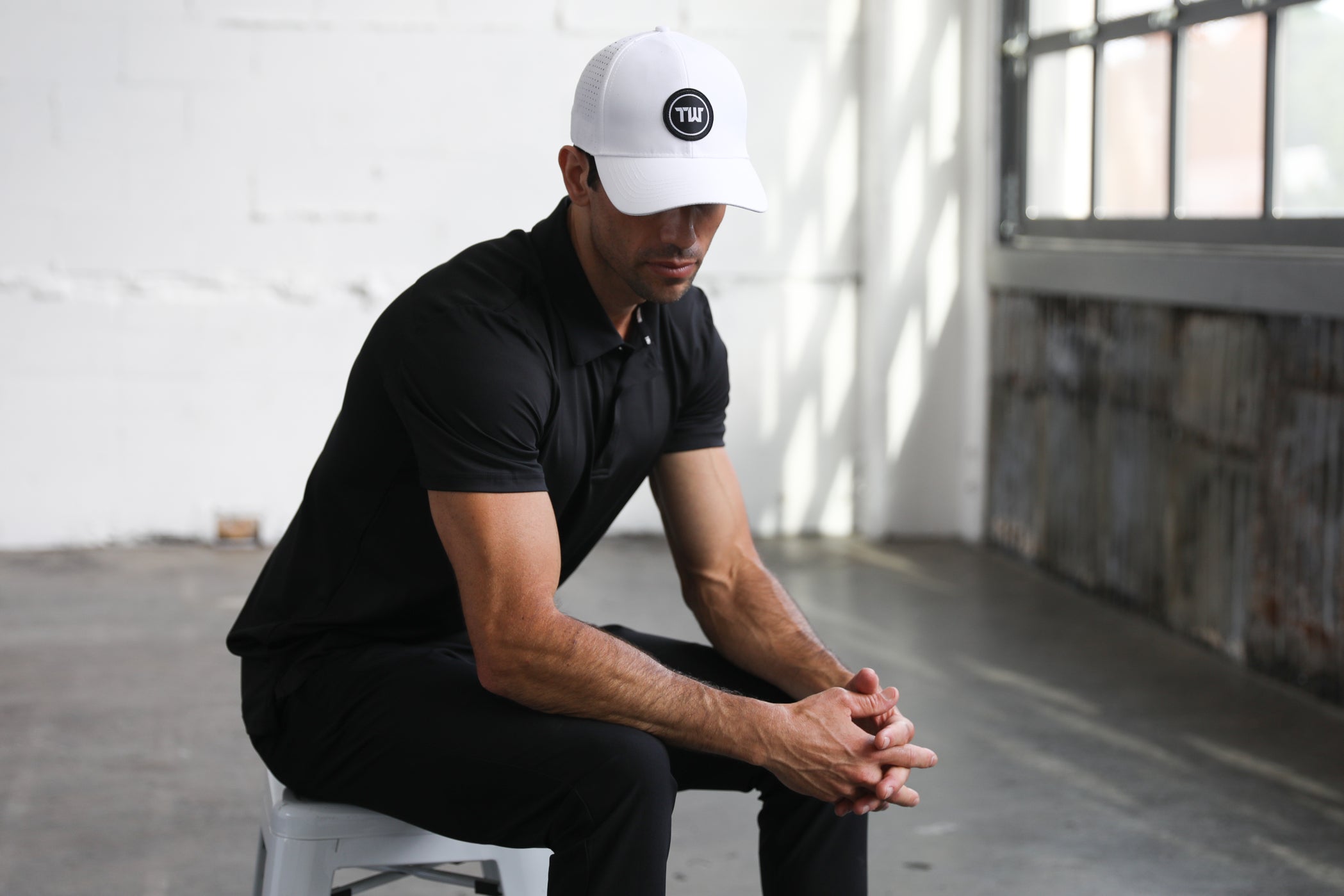 Man looking down wearing a white Truwear hat and black dress shirt and pants