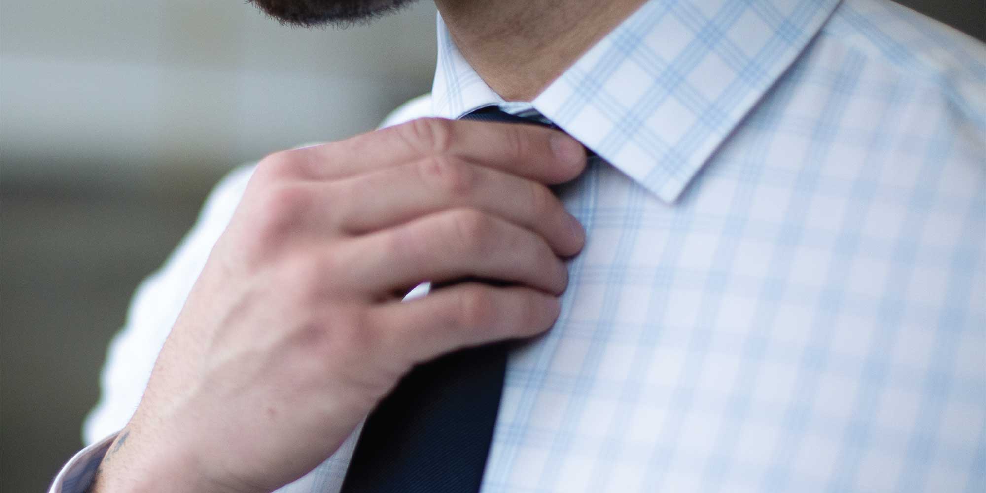 Close up on man holding tie on collared shirt